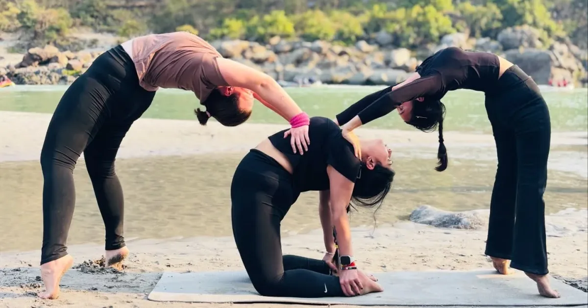 Women practising yoga on the sand beside the Ganga at Rishikesh in the early morning