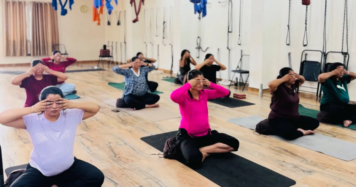 A full training hall of students seated on mats during a group practice session at Rudra Yogpeeth in Rishikesh