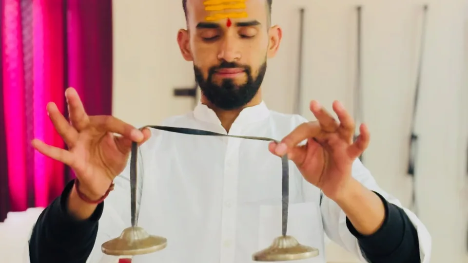 Sound healing teacher playing tingsha cymbals during a sound therapy class at Rudra Yogpeeth