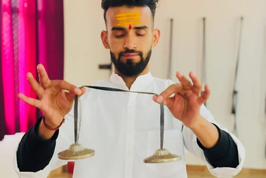 Sound healing teacher playing tingsha cymbals during chakra therapy practice in Rishikesh