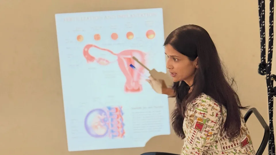 Teacher explaining prenatal anatomy from a chart during the prenatal yoga teacher training