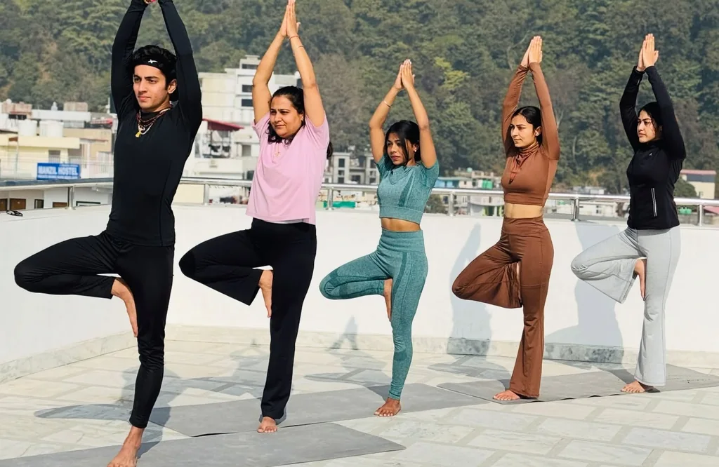 Students in tree pose on the rooftop at Rudra Yogpeeth, Rishikesh